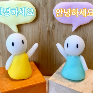黄色と水色のワンピースを着た白いキャラクターが木の台に並んで立ち、吹き出しで韓国語の会話をしている様子のイラスト